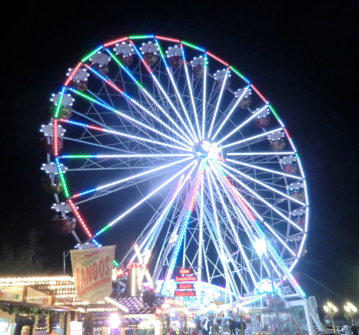 Beleuchtetes Riesenrad auf einem Jahrmarkt bei Nacht mit bunten LED-Lichtern und Fahrgeschäften auf dem Spremberger Heimatfest.
